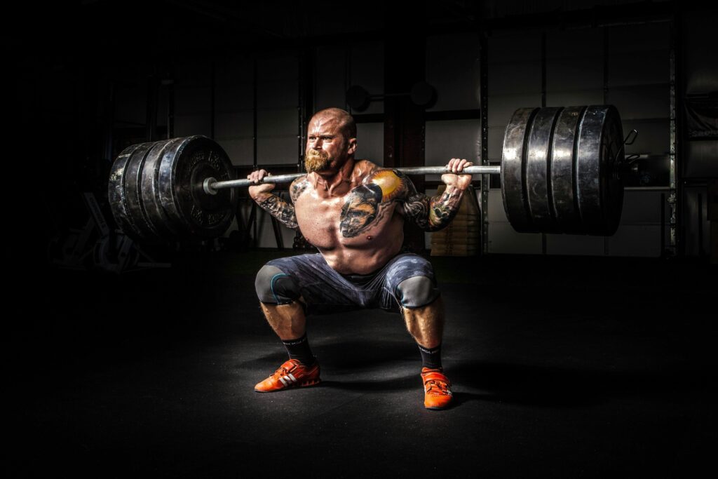 Muscular man lifting heavy weights during an intense squat session inside a gym.
