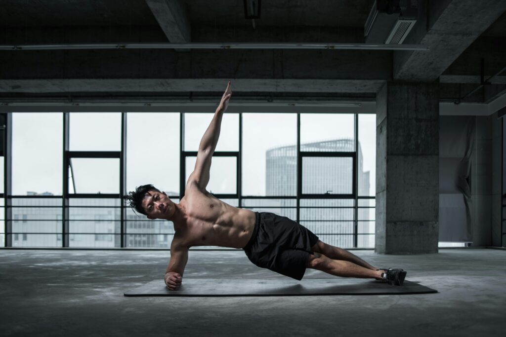 Fit man doing a side plank in an urban indoor gym, showcasing core strength and balance.
